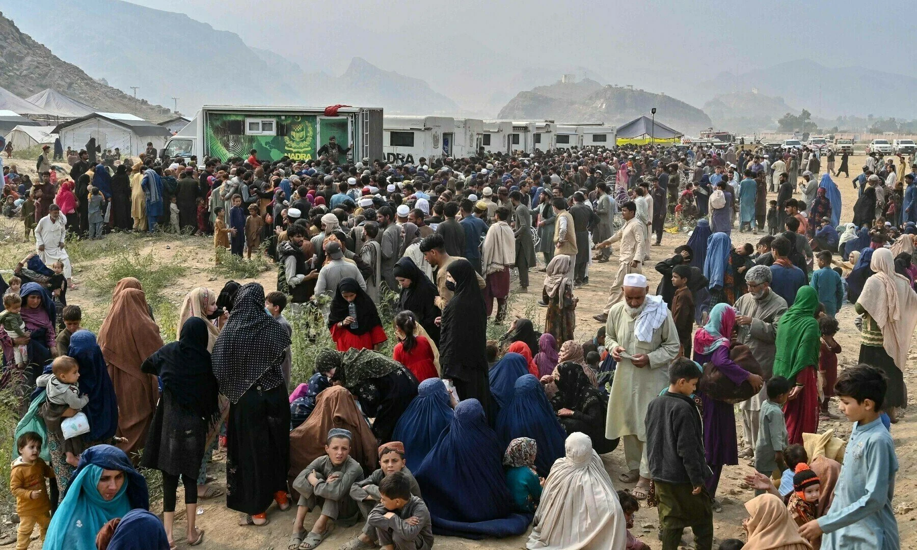 Afghan refugees gather around National Database and Registration Authority (Nadra) vans for biometric verifications as they prepare to depart for Afghanistan, at a holding centre in Landi Kotal on Nov 1. [AFP]