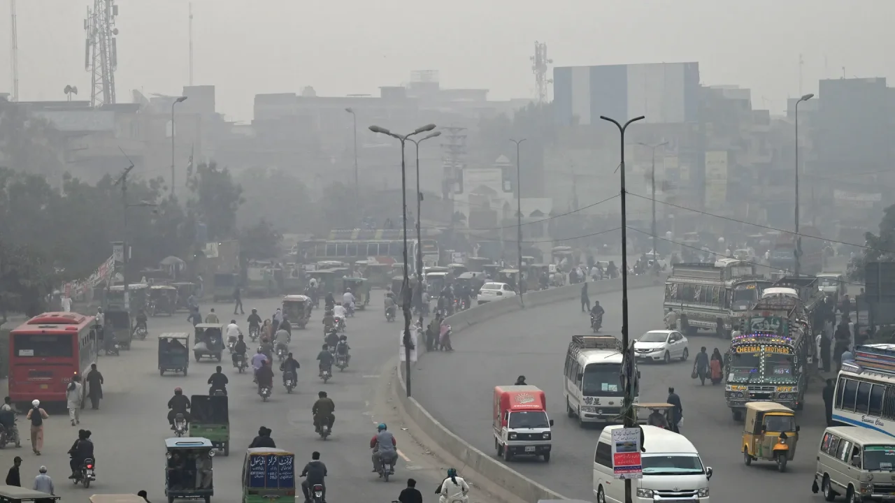 Commuters make their way through a busy street amid smoggy conditions in Lahore [AFP]